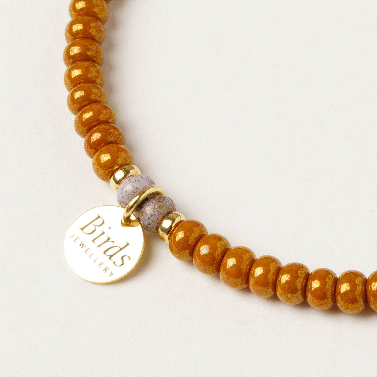 Detalhe da medalha em prata 925 dourada da pulseira Caramelo & Areia Birds Jewellery.