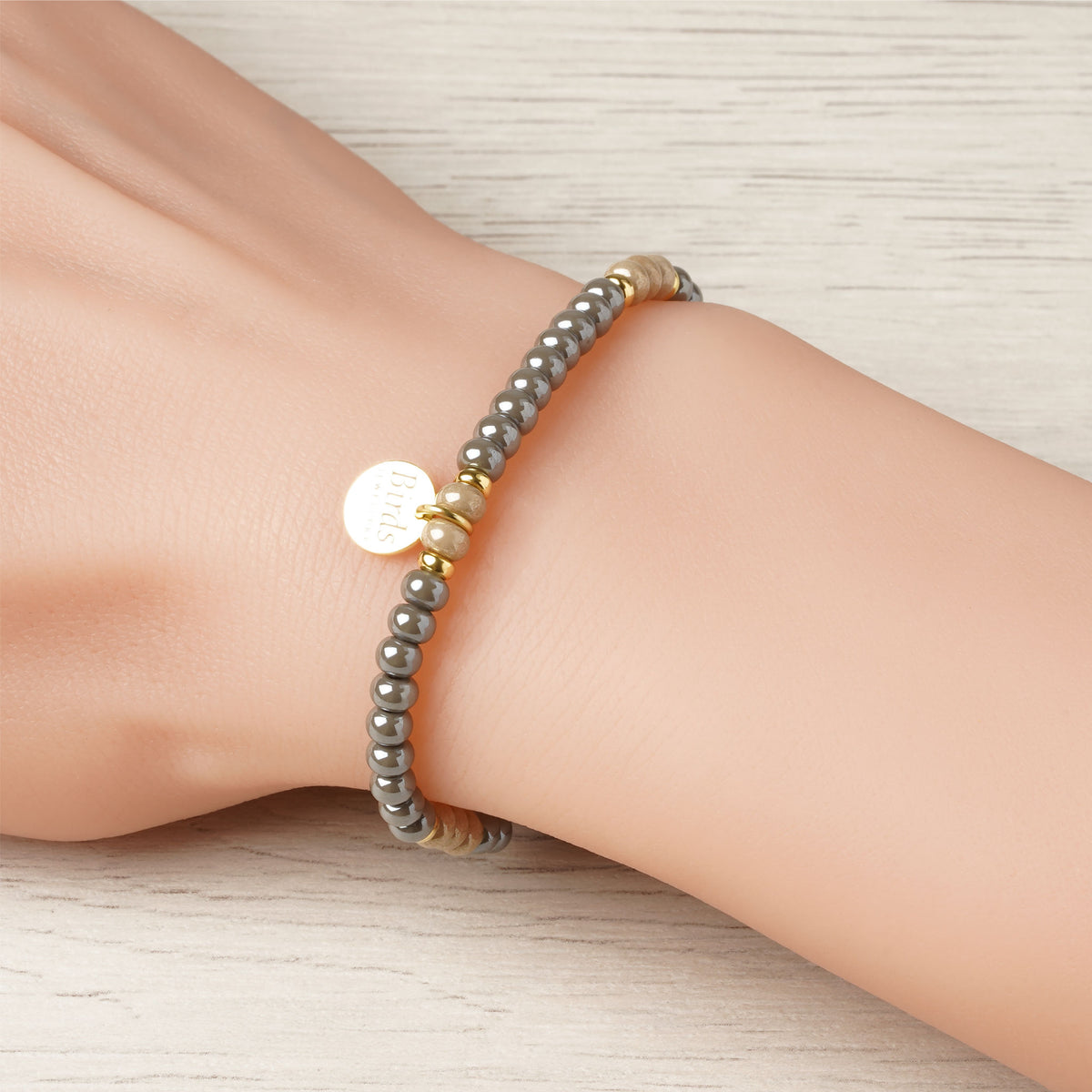Pulseira Cinzento & Bege em cristal boémio e prata 925 dourada ajustada no pulso feminino.