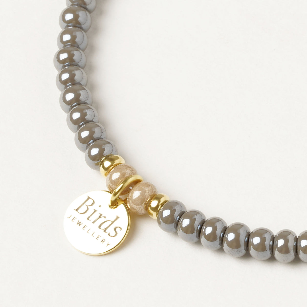 Detalhe da medalha em prata 925 dourada da pulseira Cinzento & Bege Birds Jewellery.