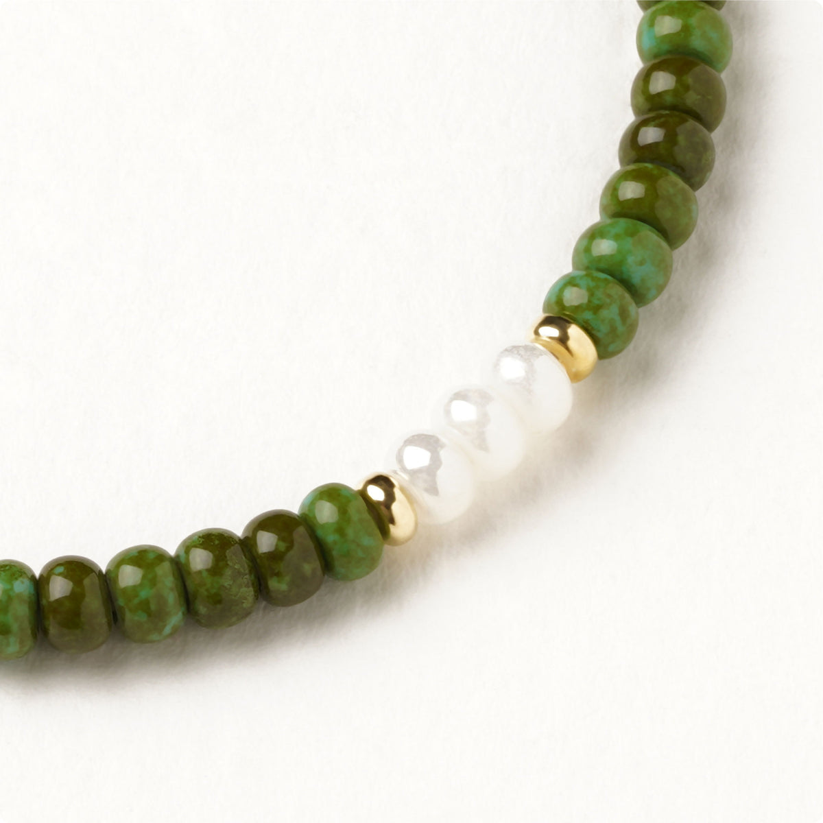 Vista aproximada das contas em cristal boémio verde alpino e branco perolado da pulseira Birds Jewellery.