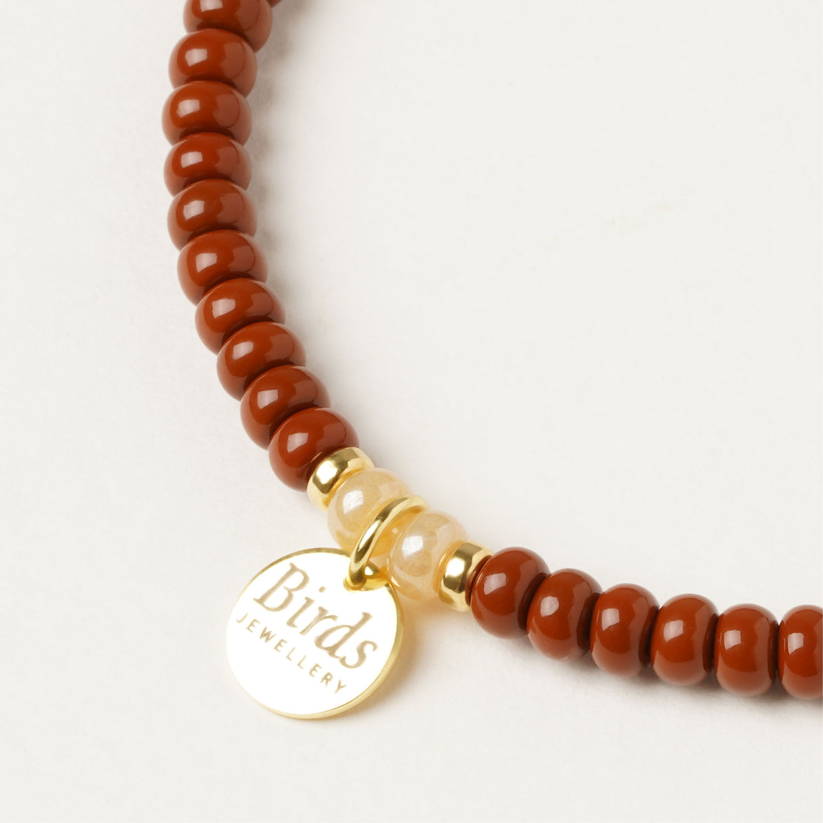Detalhe da medalha em prata 925 dourada da pulseira Castanho, Creme & Areia Birds Jewellery.