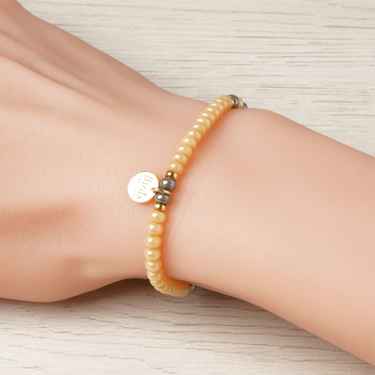 Pulseira Mel & Cinzento em cristal boémio e prata 925 dourada ajustada no pulso feminino.