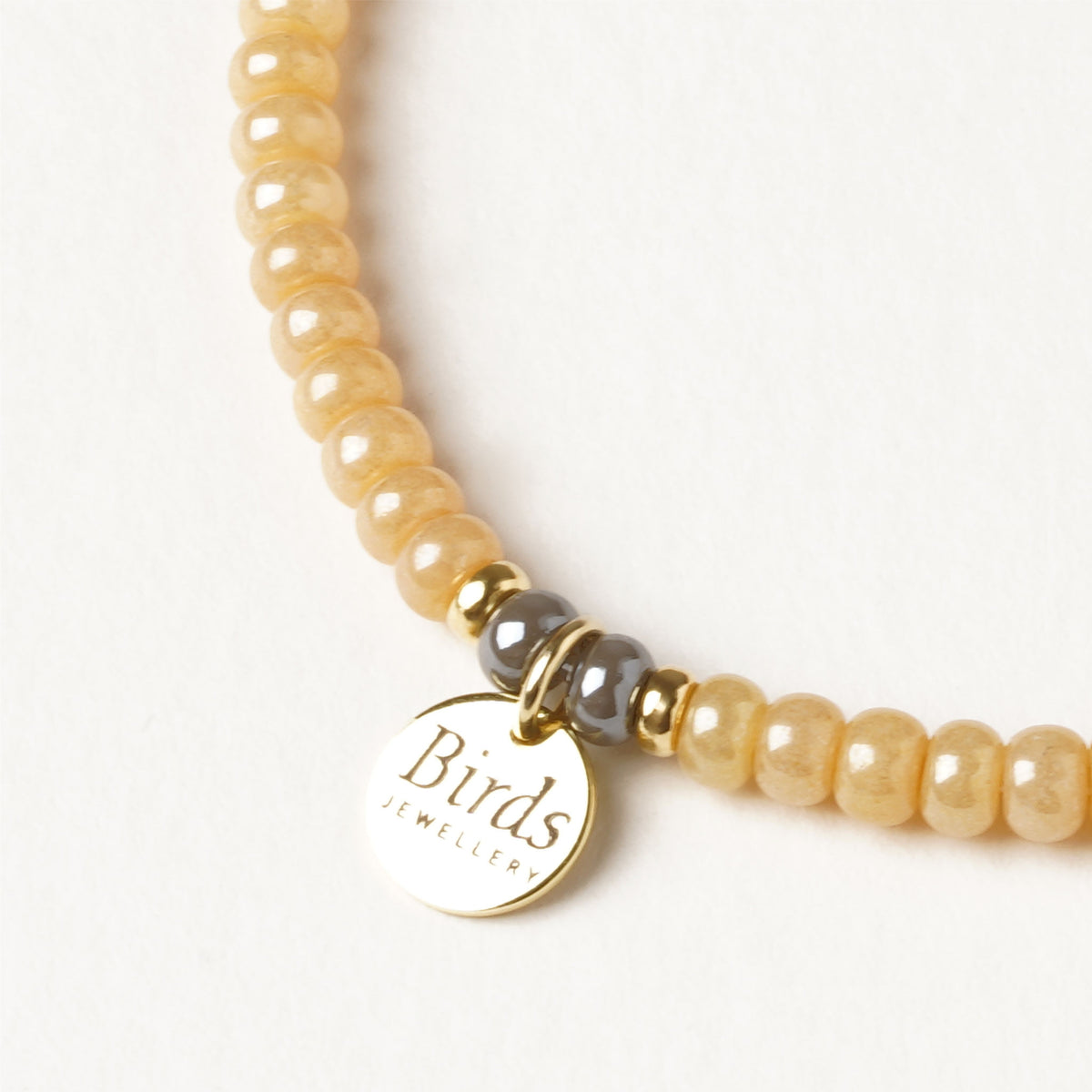 Detalhe da medalha em prata 925 dourada da pulseira Mel & Cinzento Birds Jewellery.